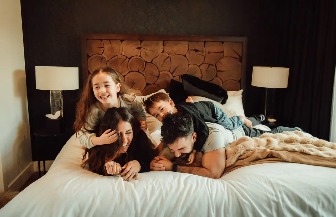 Family piled on a bed, laughing