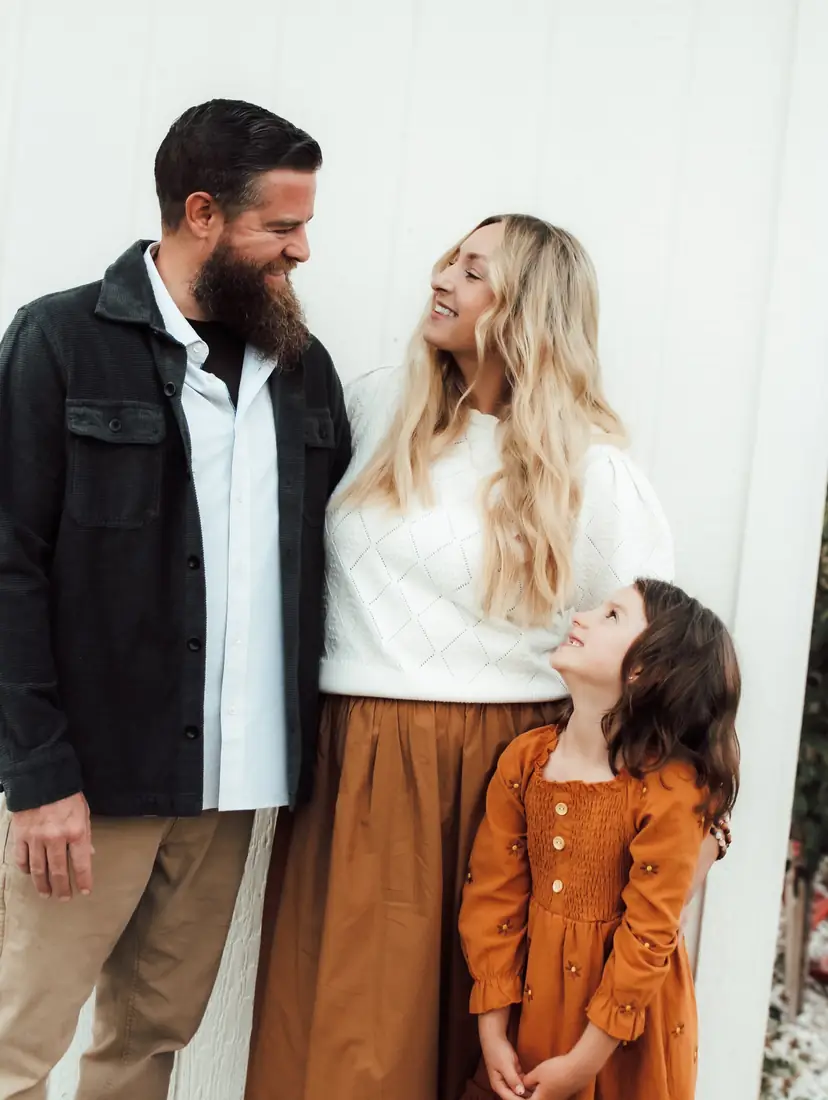 Family smiling at each other in front of a cream wall